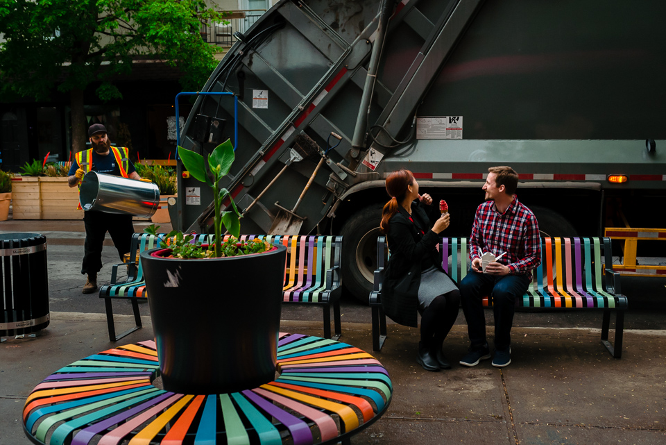 Garbage truck passing by engaged couple on bench