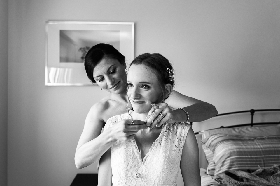 Friend putting necklace on bride