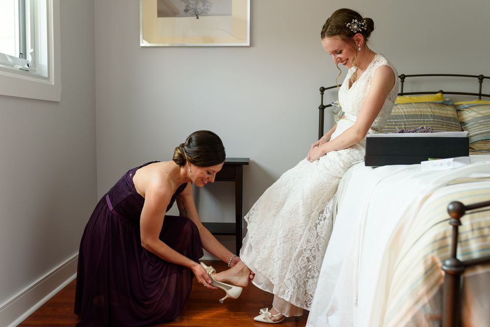 Friend putting shoe on bride