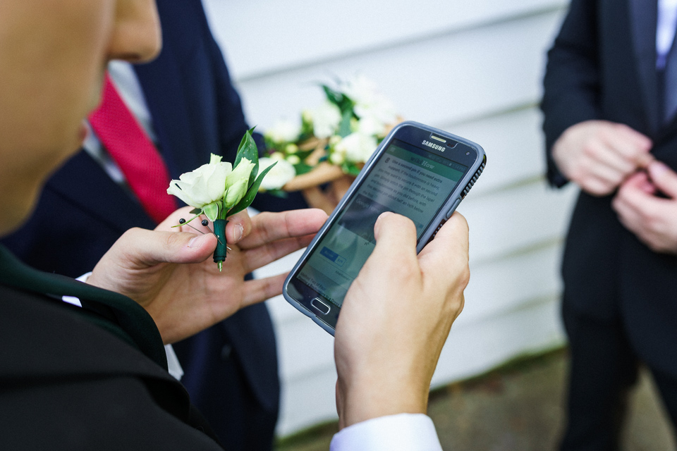 Groomsmen looking up video on how to pin flower on