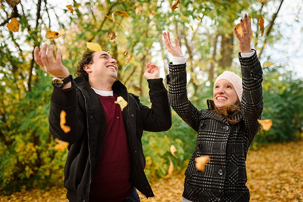 Engaged couple throwing leaves in the air