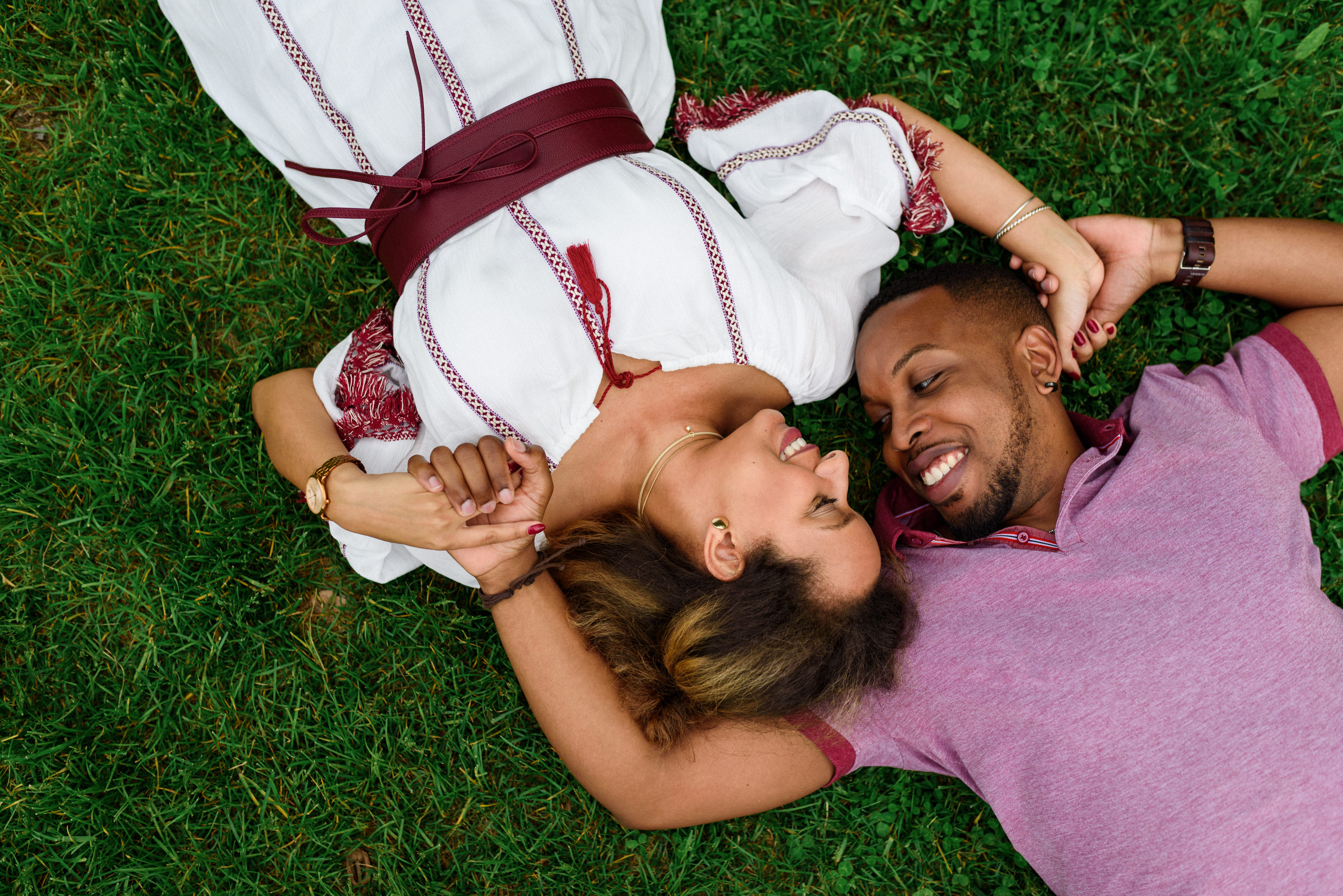 Engagement photo of couple lying in grass and holding hands