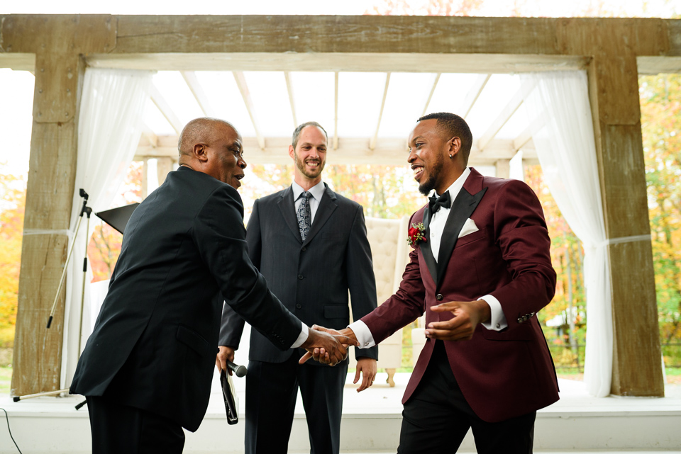 Groom and father shaking hands at wedding ceremony