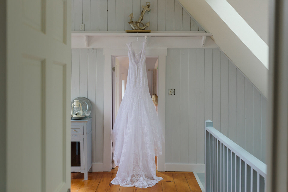 Bride wedding dress hanging up in a pale cottage doorway