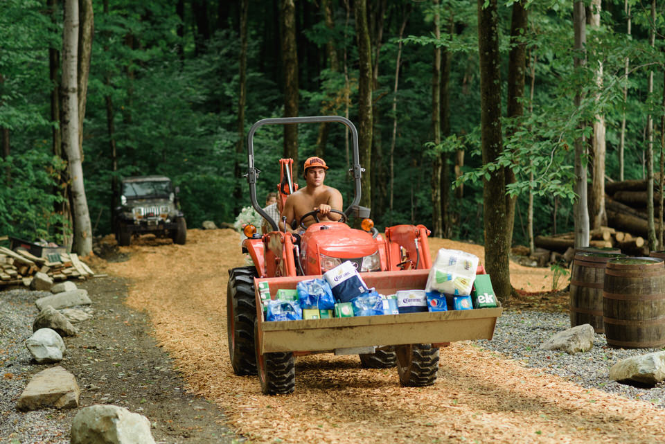 Man driving small tractor carrying wedding party supplies up a gravel road on a hill