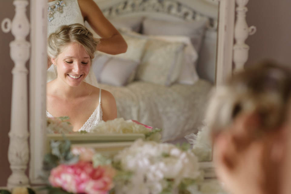 Bride laughing in mirror as she gets her hair done