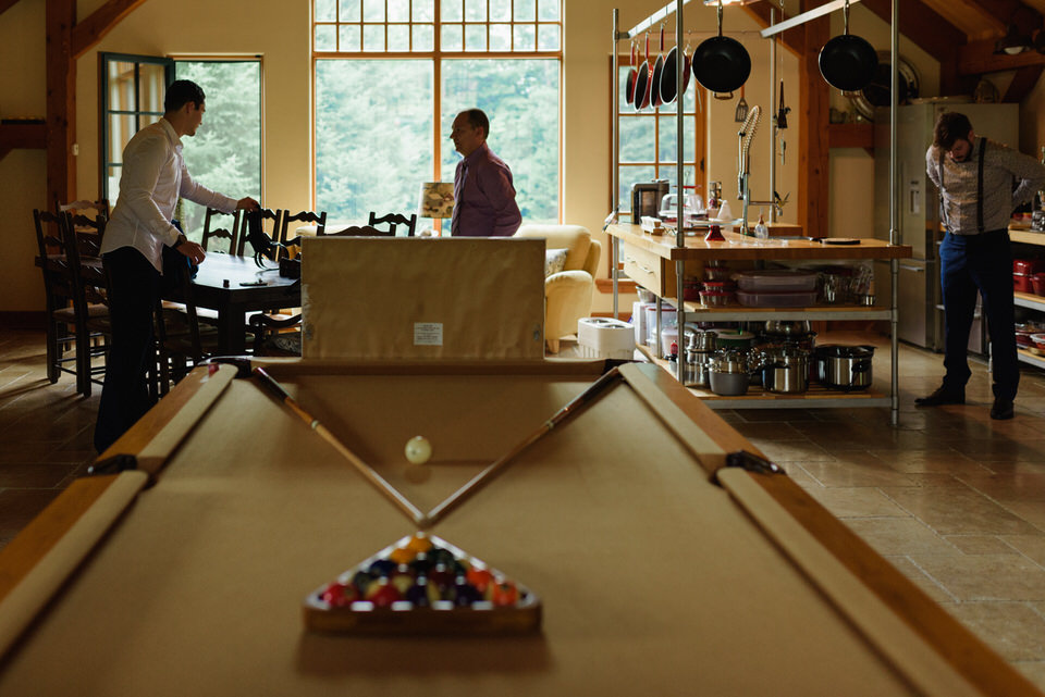Wide room photo of a cabin with pool table and groom getting ready