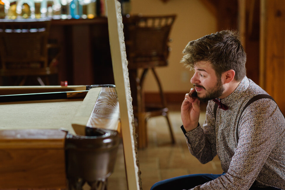 Groomsman brushing his beard and looking in the mirror