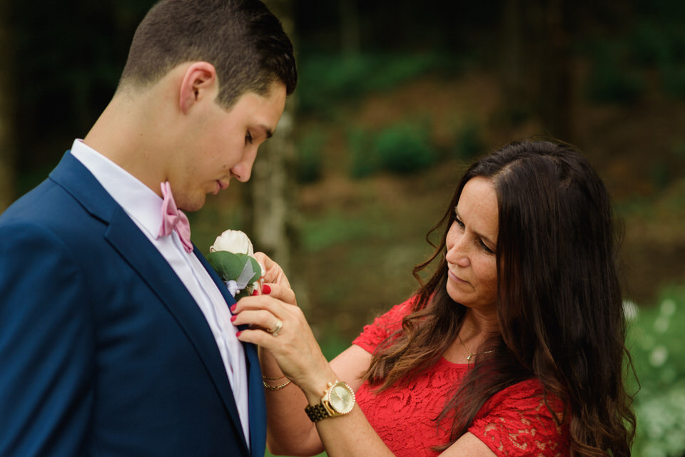 Groom's mom helping him pin on boutonniere