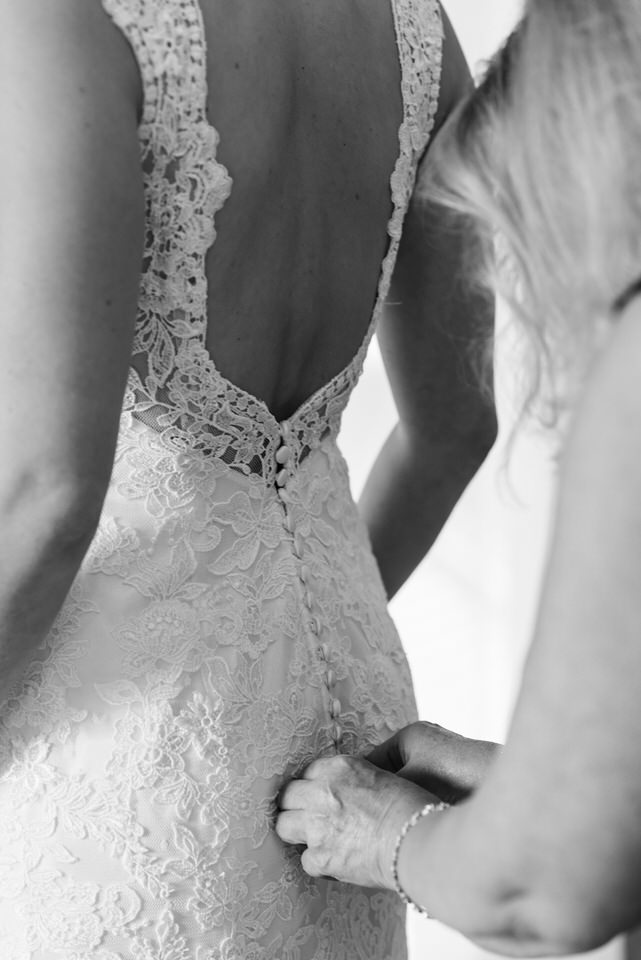 Mom buttoning up her daughter's wedding dress