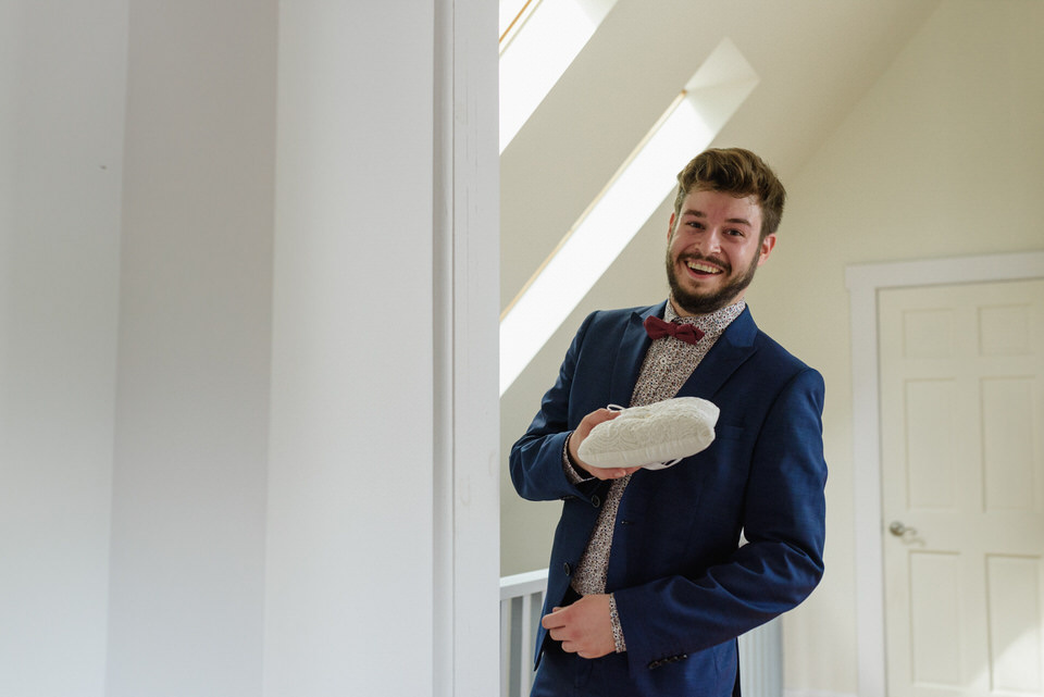 Groomsman peeking around the doorway holding the rings