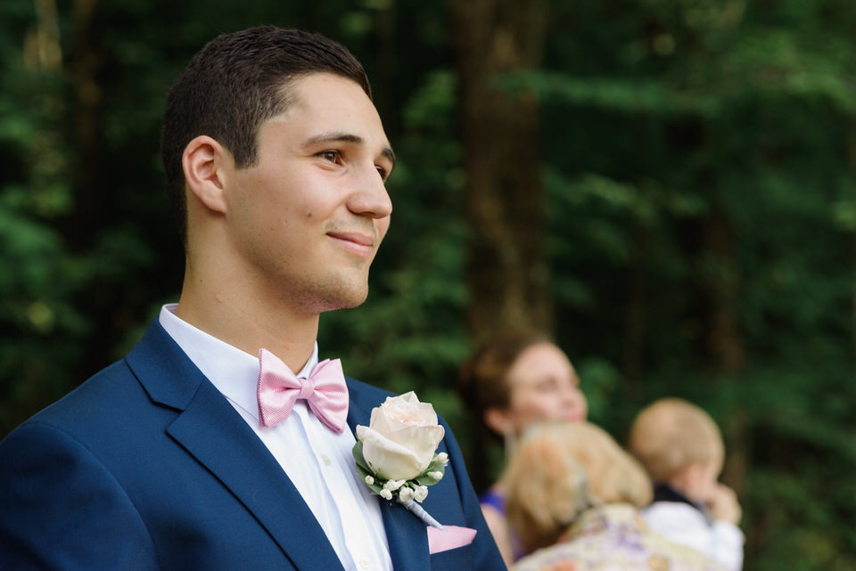 Groom watching bride approach in outdoor rustic ceremony