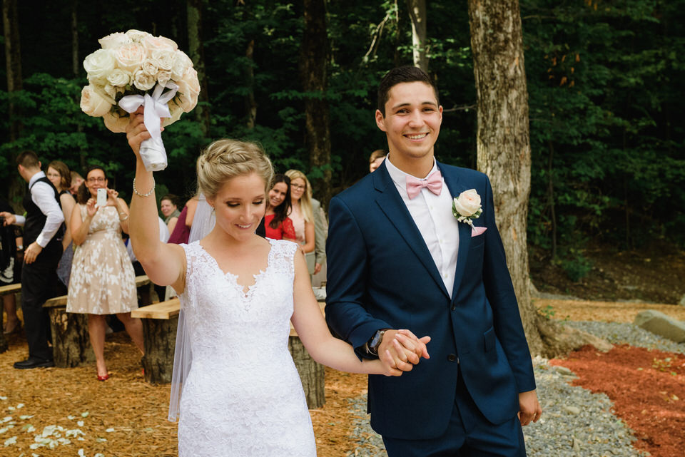 Bride raising up her bouquet after rustic wedding