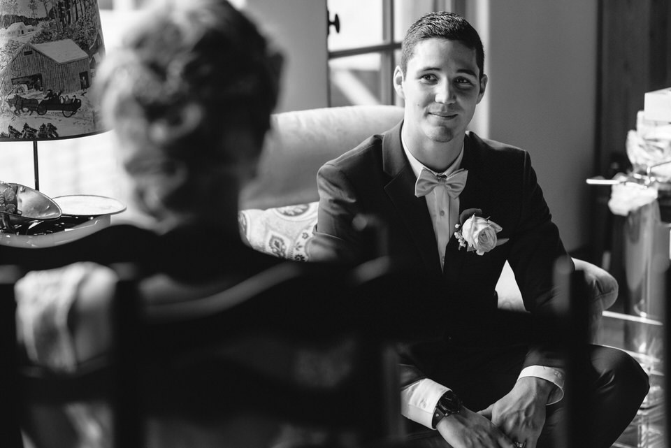 Groom looking at bride inside rustic cabin