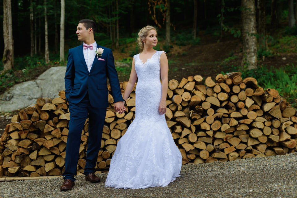 Wedding portrait in front of pile of wooden logs