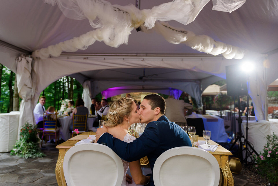 Bride and groom kissing at wedding reception under tent