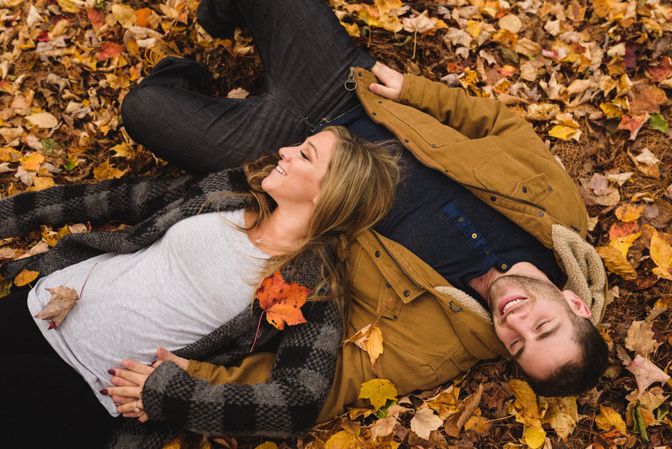 Engaged couple lying in fall leaves