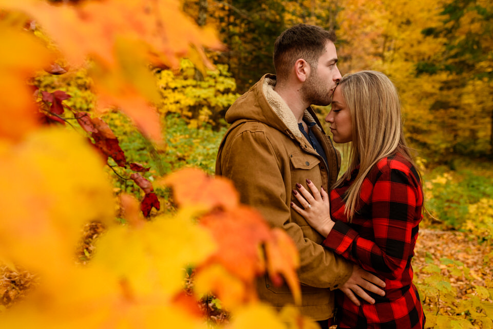 Couple kissing framed by bright orange colourful leaves