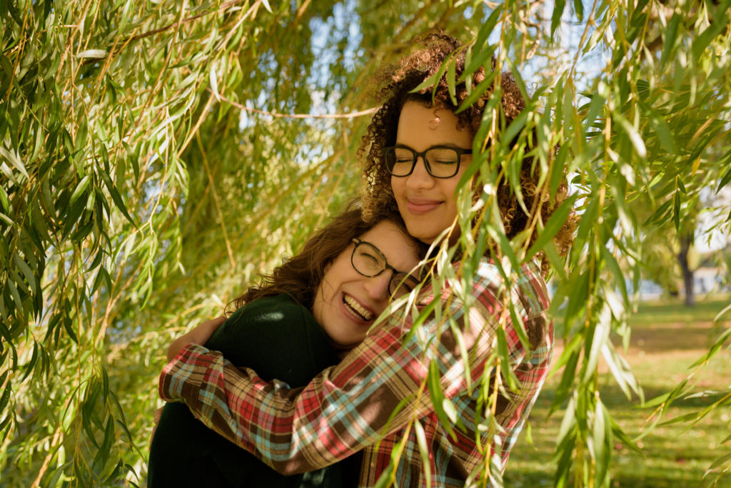 Two women hugging under willow leaves