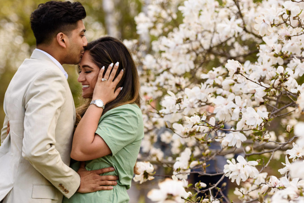 Engaged couple hugging surrounded by blossoms at Botanical Gardens