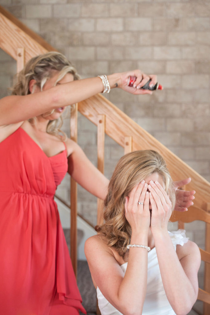 Bridesmaid hairspraying her sister