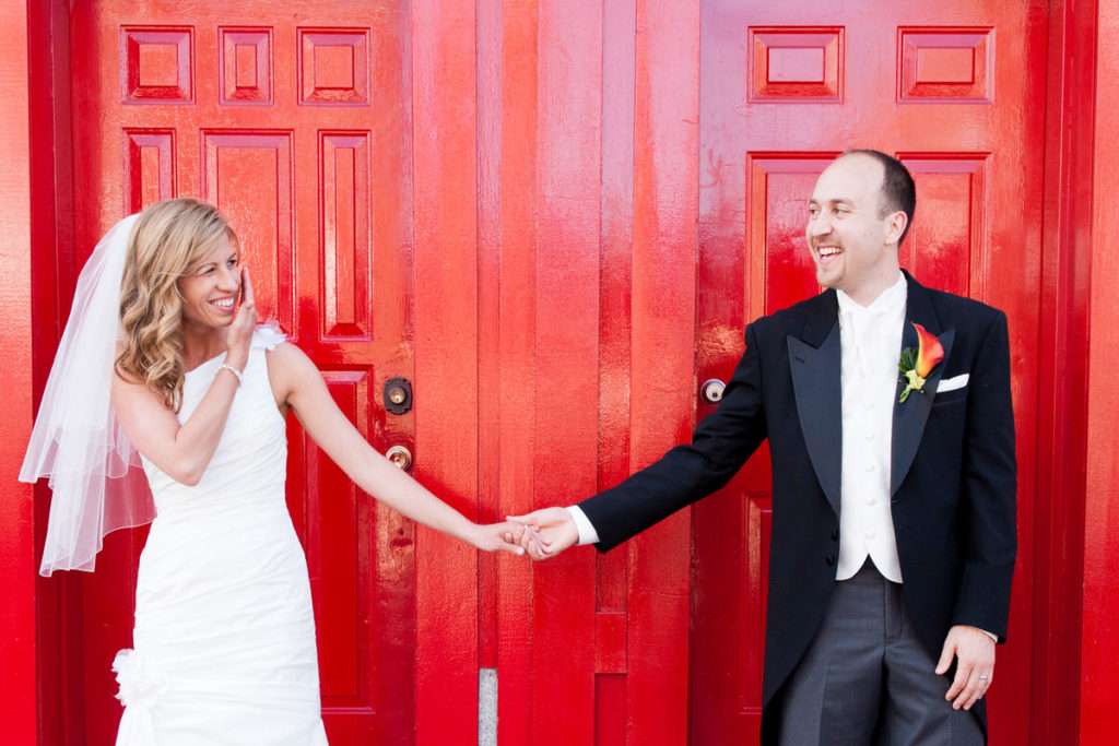 Bride and groom taking a picture in front of a red door