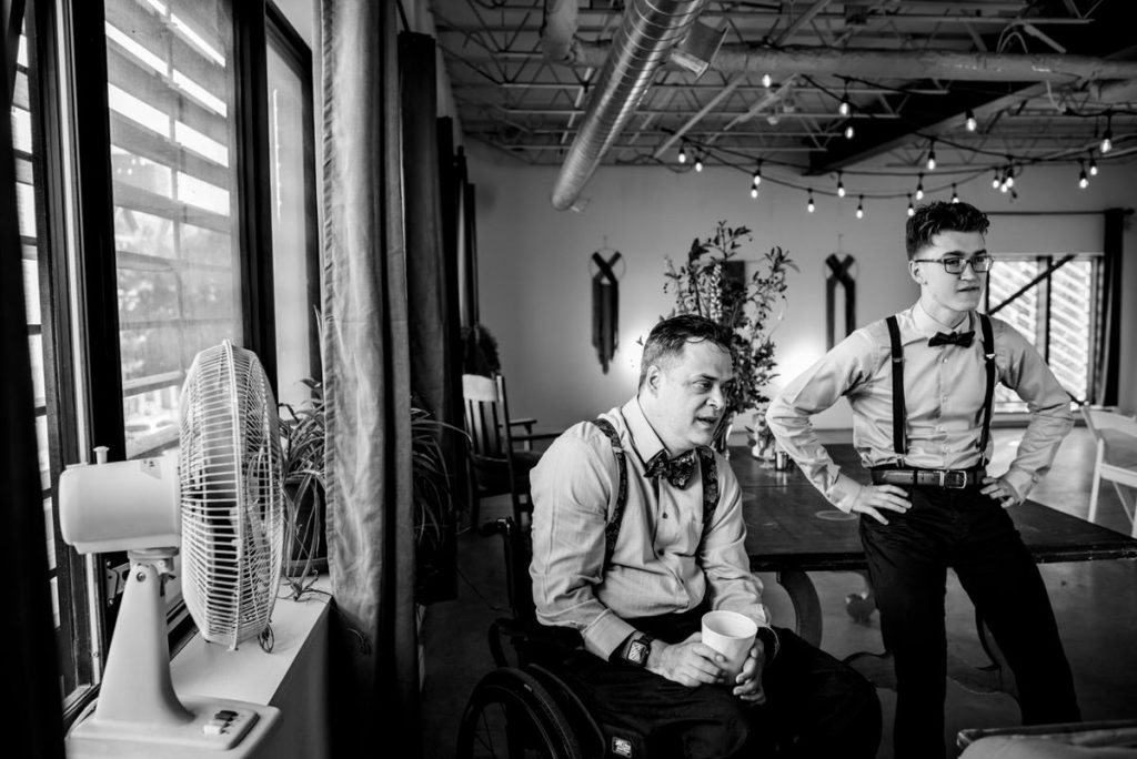 Groom cooling off near fan on hot wedding day