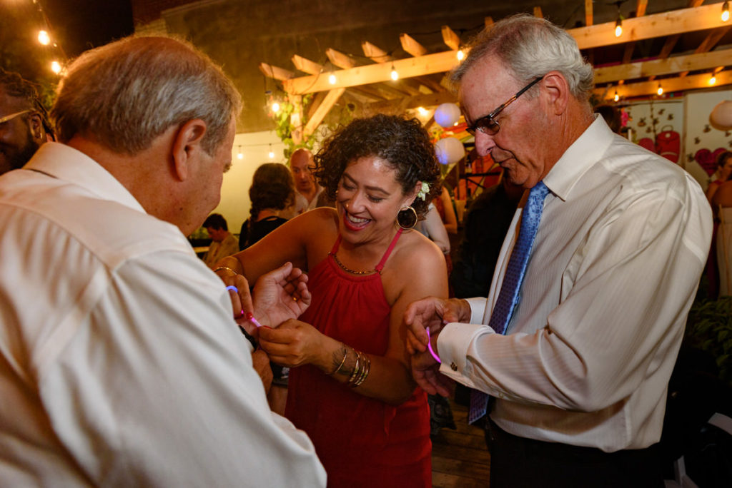 Maid of honour giving the bride's father a glow stick bracelet
