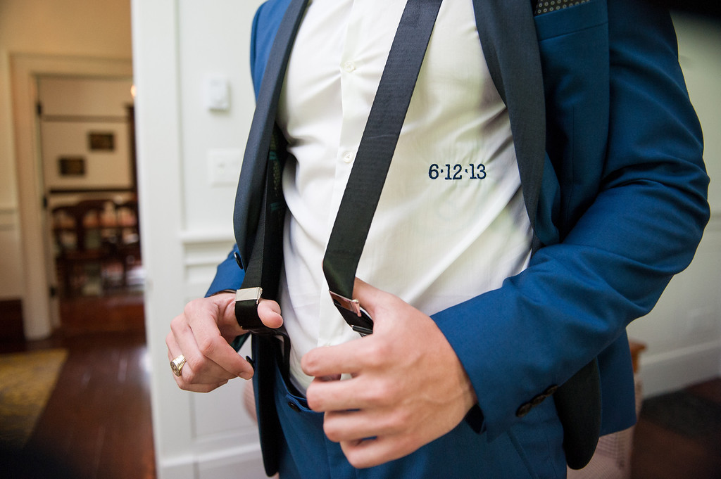 Groom tugging his suspenders with wedding date embroidered on his shirt
