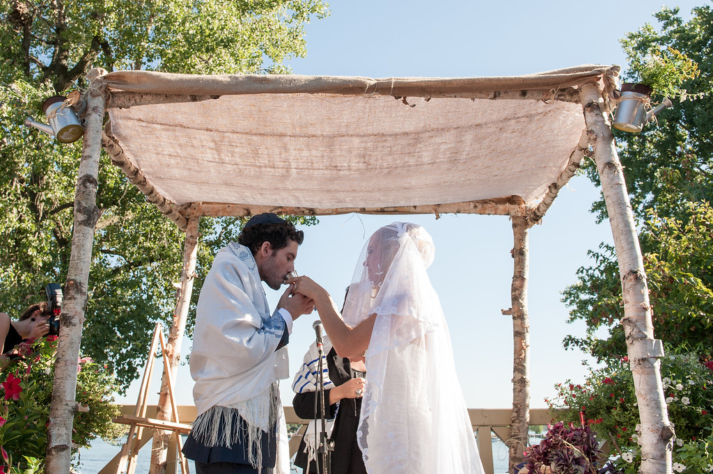 Groom drinking from cup under huppah