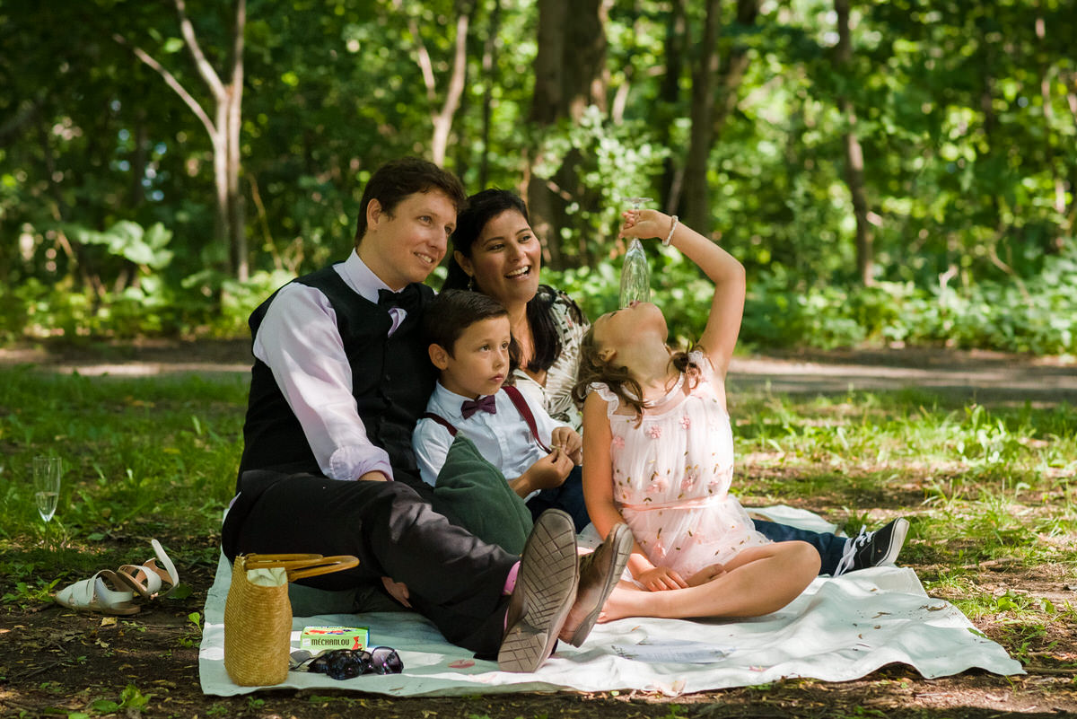 Family sitting on blanket at pandemic wedding in a park