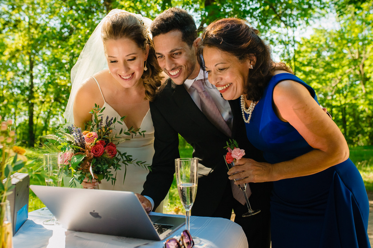 Bride, groom and his mom video chat with family during COVID wedding in a park