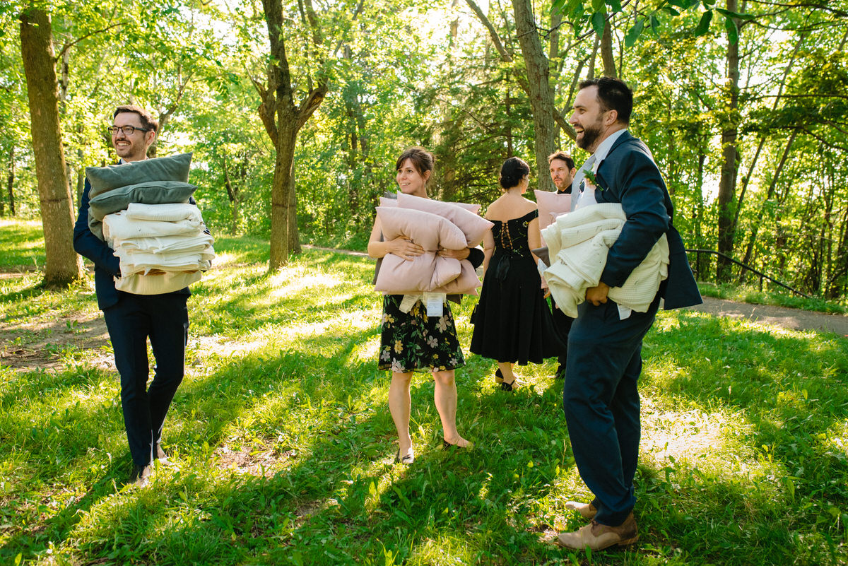 Friends carrying away cushions and blankets from the wedding in a park