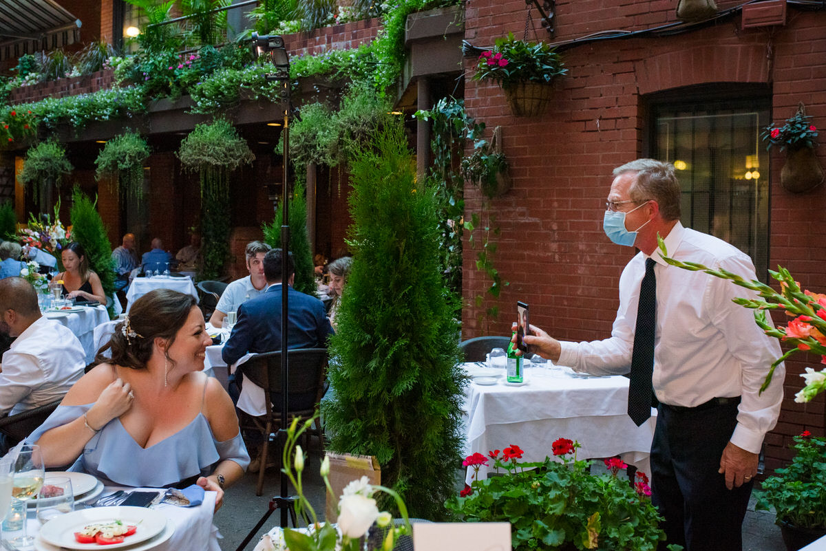 Father of the bride holding a phone so virtual guests can video chat at pandemic wedding