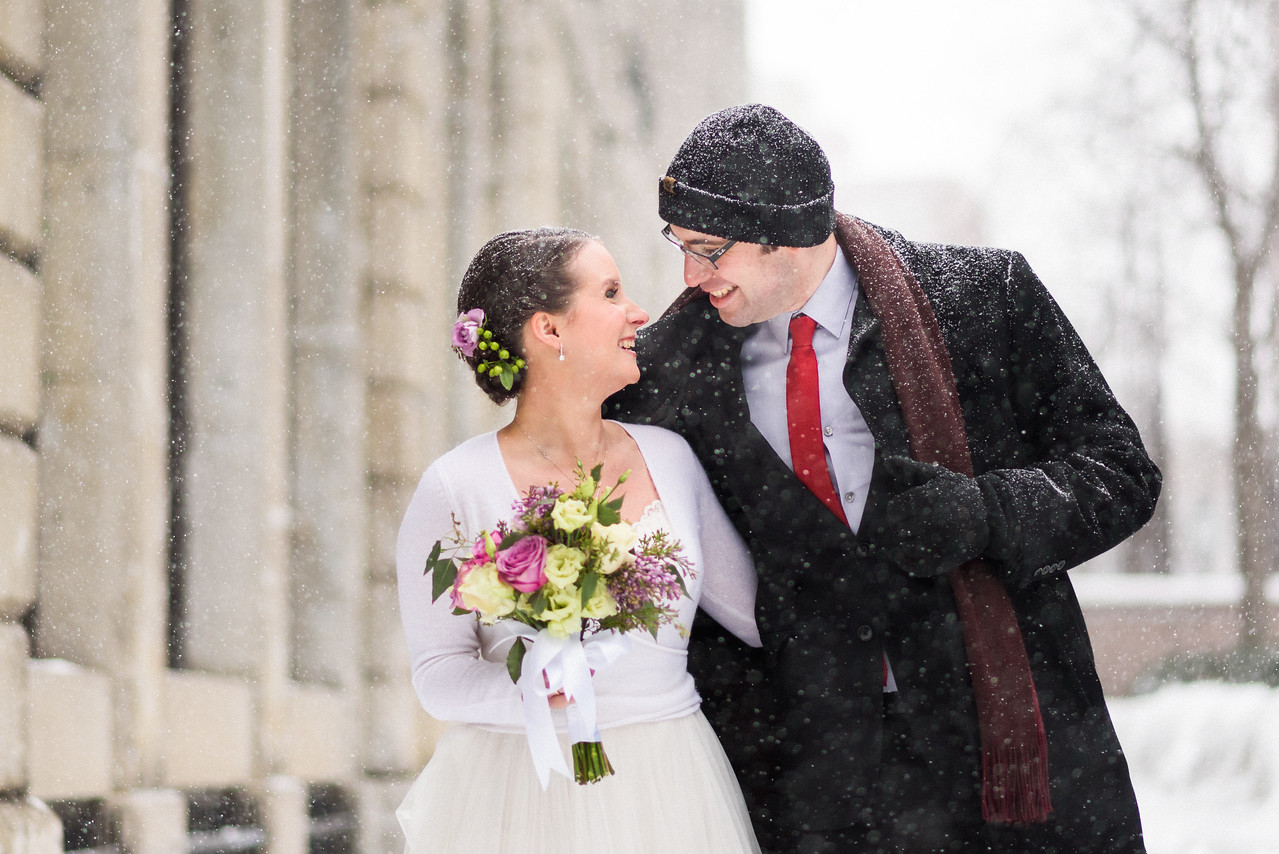 Groom holding his coat open to warm bride during winter photo