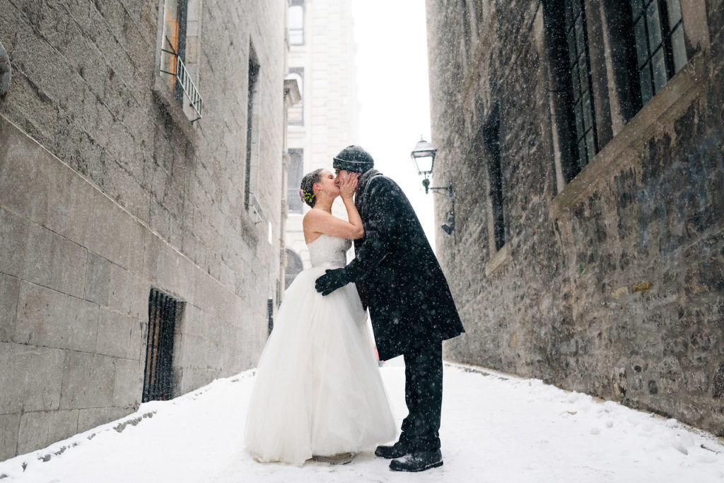 Winter wedding in Old Montreal as couple kisses in the snow