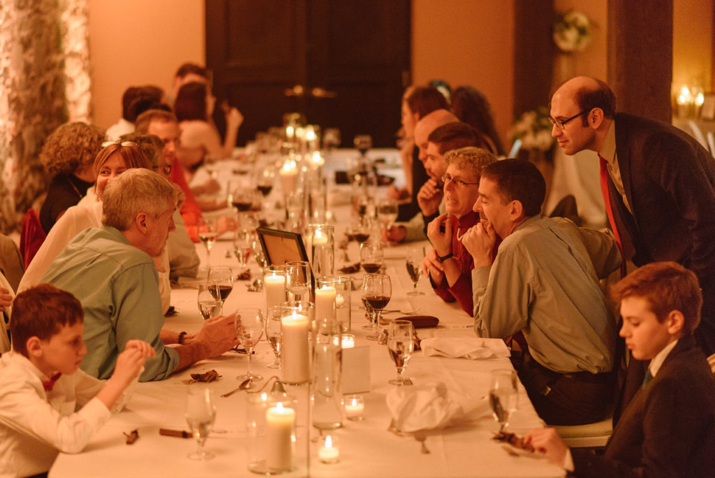 View of wedding table by candlelight with guests chatting