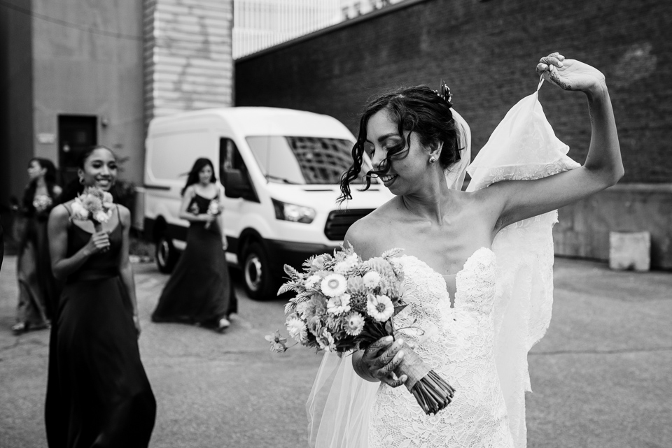 Bride walking while holding up her dress in the wind