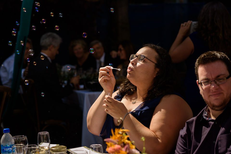 Wedding guest blowing bubbles at outdoor wedding dinner
