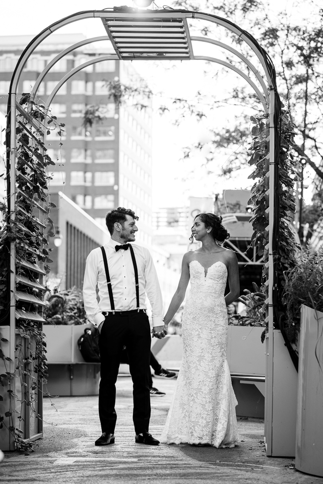 Wedding couple holding hands and standing in a archway on the street