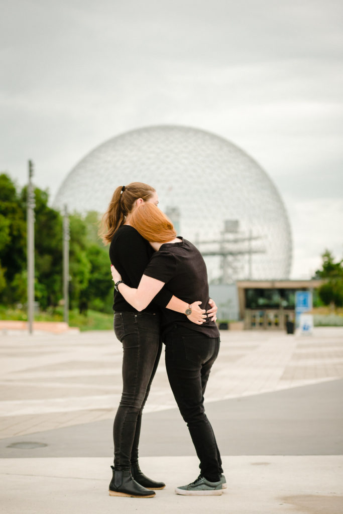 Couple hugging after proposal with the Montreal Biosphere in background